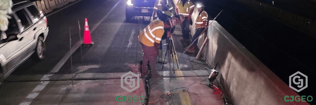 CJGeo crew performing bridge approach sleeper slab repair on I-81 at night, using specialized equipment and illuminated by work lights.