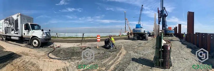 Compaction grouting operation by CJGeo on a Chesapeake Bay Bridge Tunnel (CBBT) island, showing a service truck, pumping equipment, and drilling rig stabilizing an electrical duct bank.