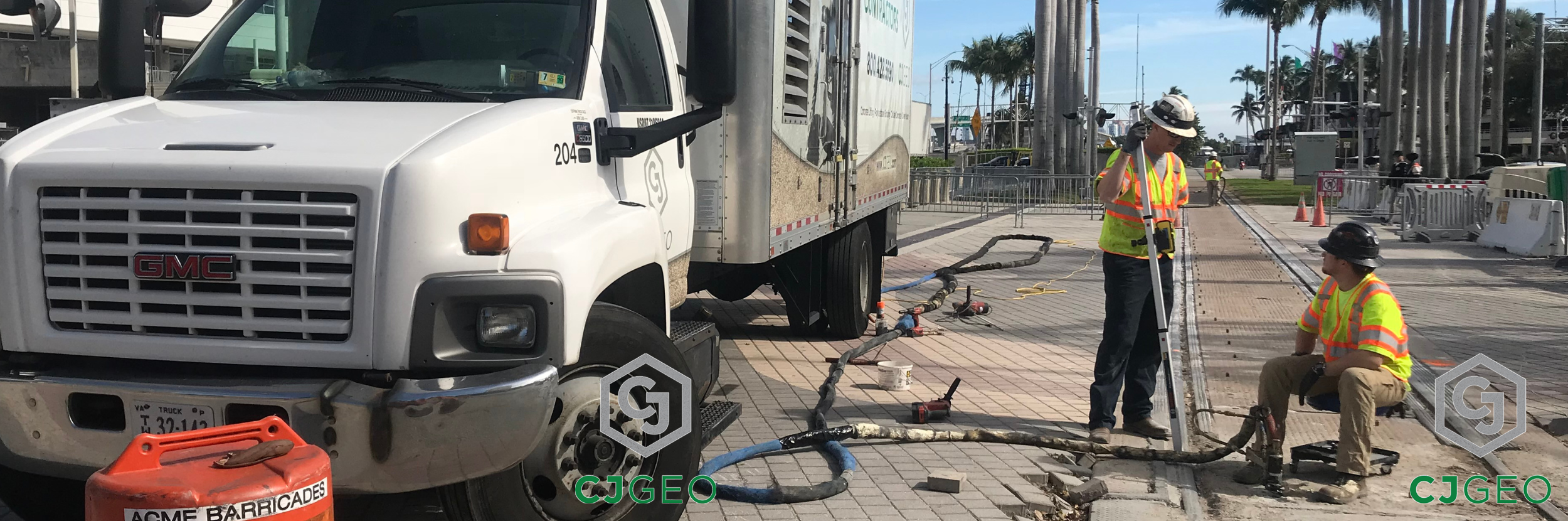A CJGeo grouting truck sitting adjacent to a modular grade crossing with workers injecting polyurethane grout under the crossing panels.