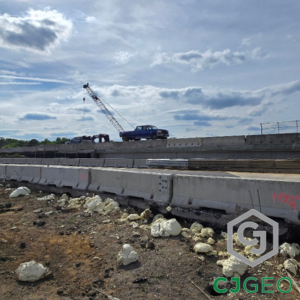 Polyurethane grout chunks on the ground next to a Jersey wall and interstate on a construction site. 