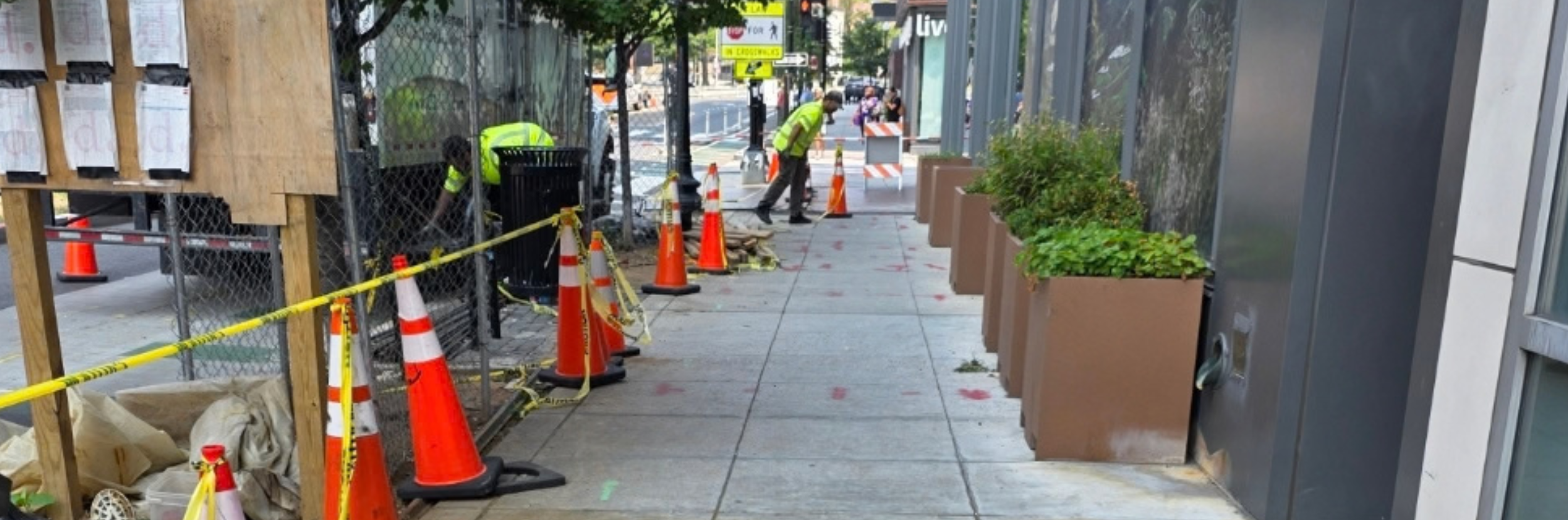 An urban construction site on a sidewalk with cones and a polyurethane grouting truck.