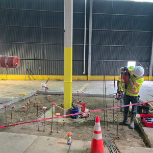 a worker installing polyurethane compaction grouting tubing around a column in a warehouse