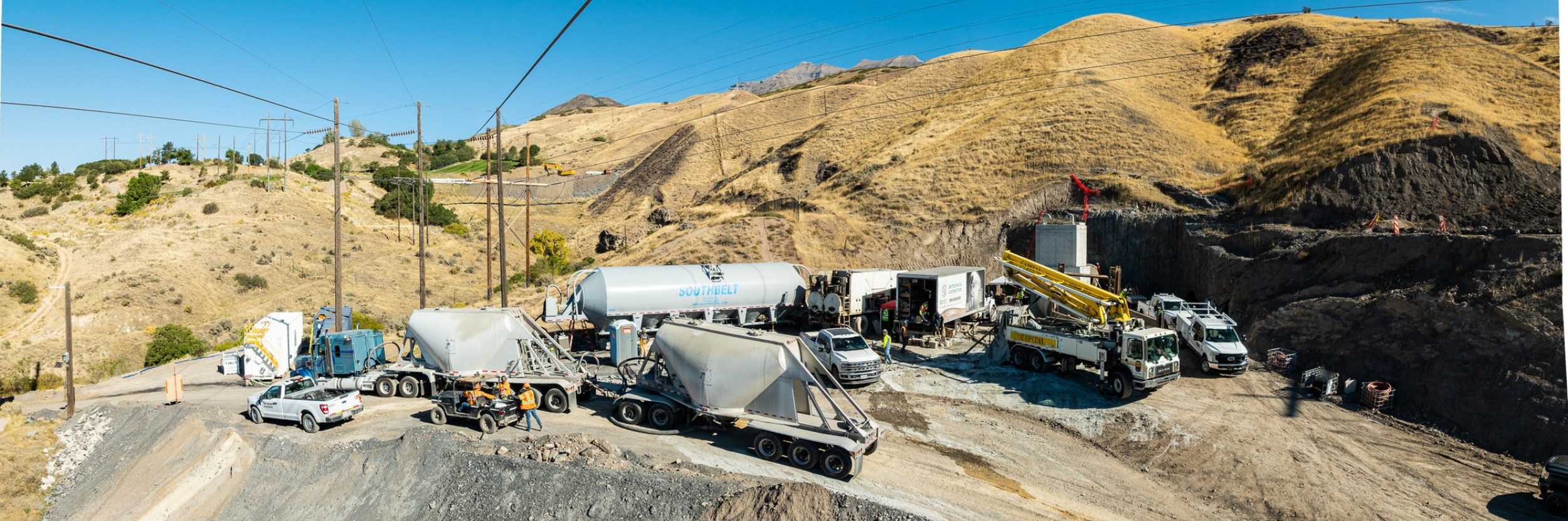 A western mountain slope with heavy construction grouting equipment at a landing pad.